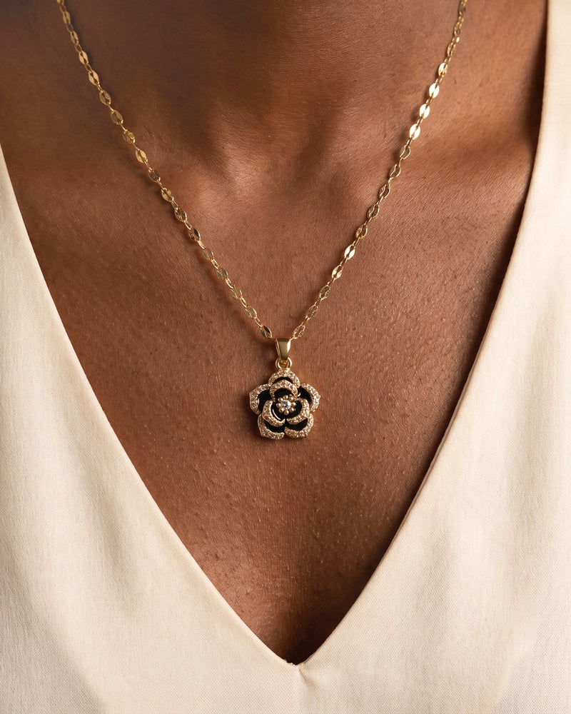 Collier Rose Noire Bellurr porté sur un haut ivoire, pendentif rose noire et dorée