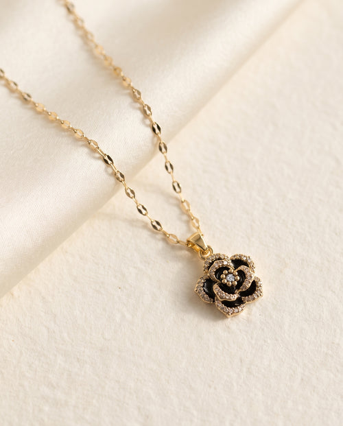 Collier Rose Noire Bellurr posé sur papier crème et satin ivoire