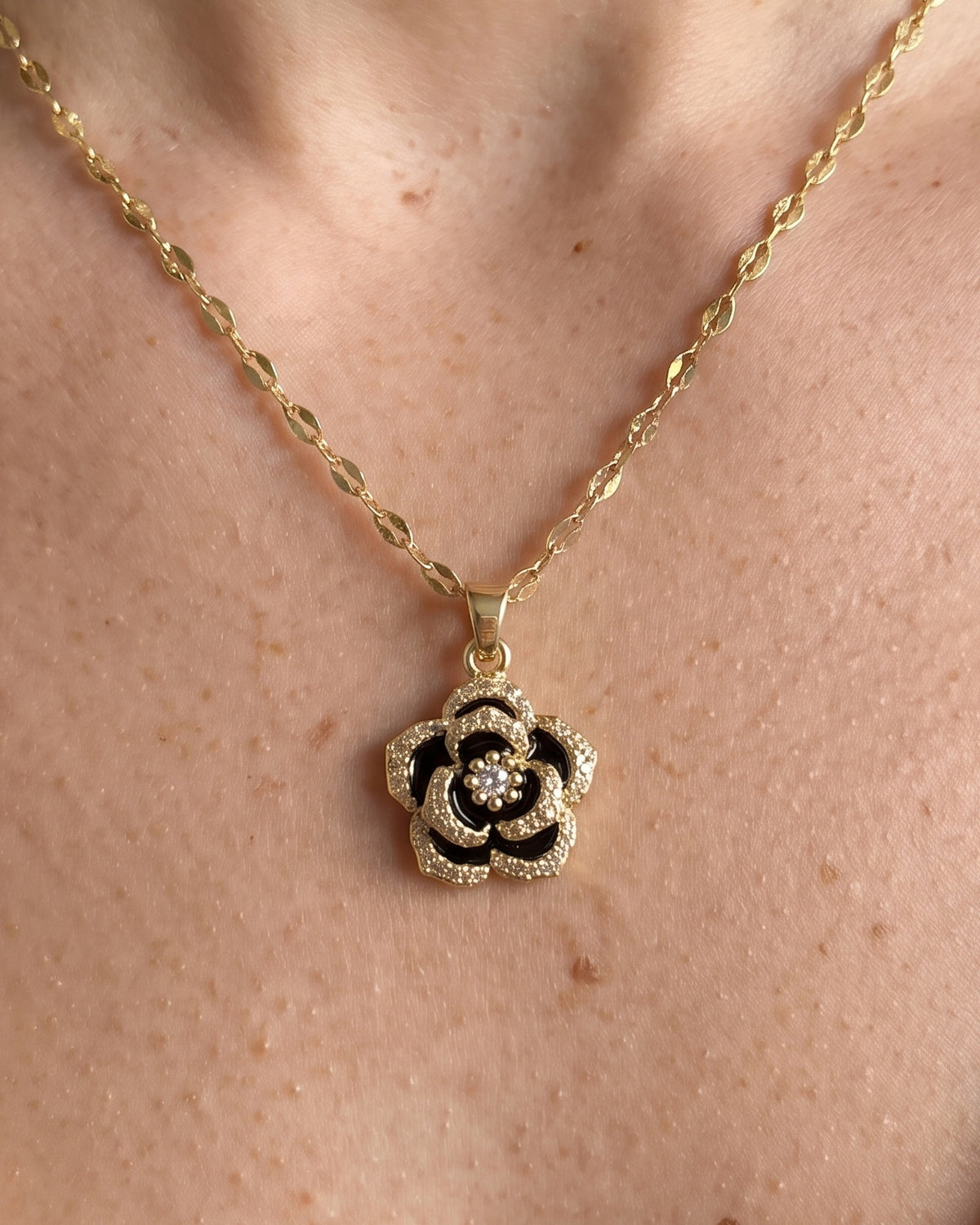 Gros plan du pendentif rose noire et dorée du collier Rose Noire Bellurr